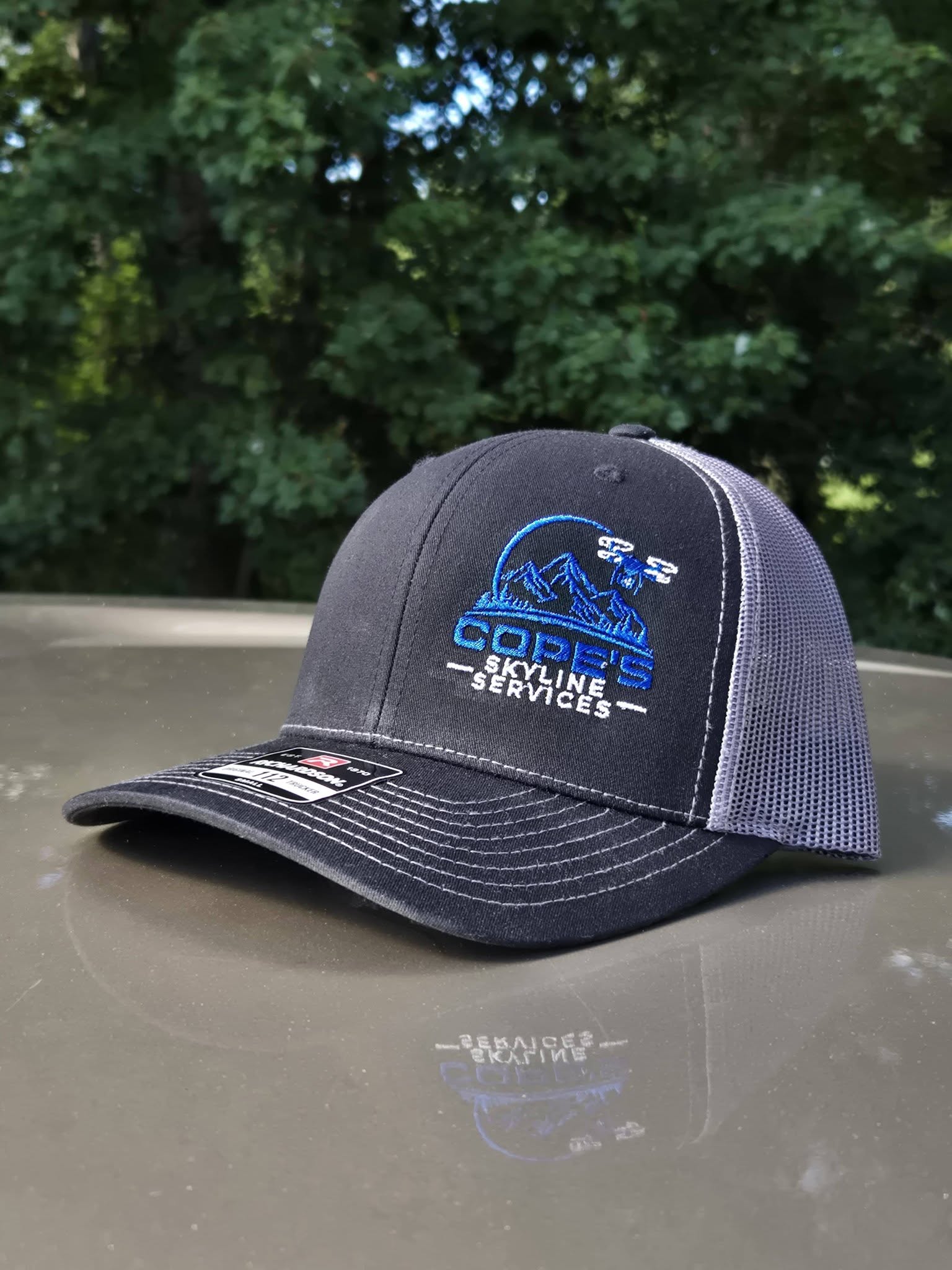 charcoal and silver embroidered hat with blue and white drone services logo