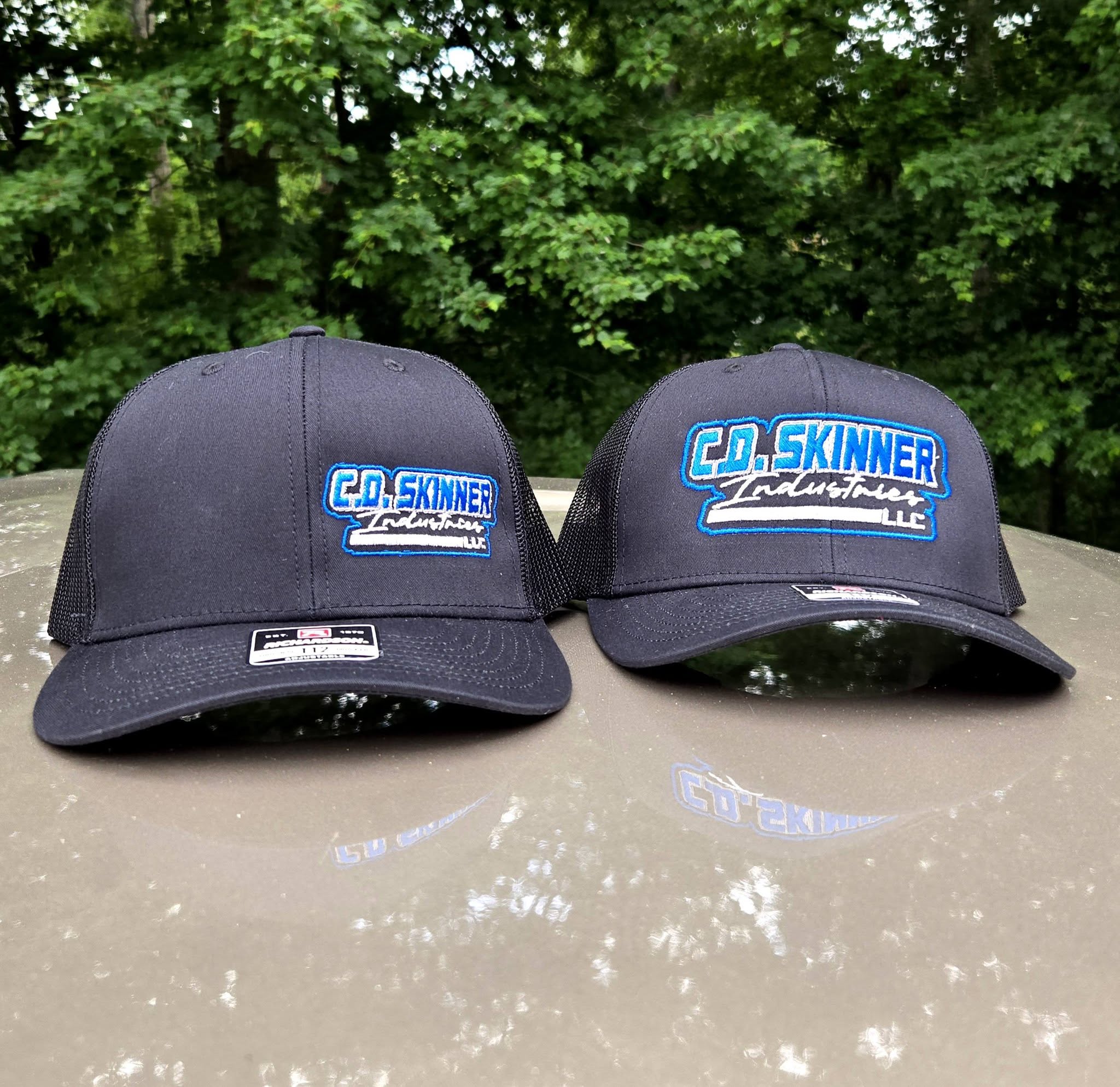 black embroidered hats with blue and silver trucking company logos
