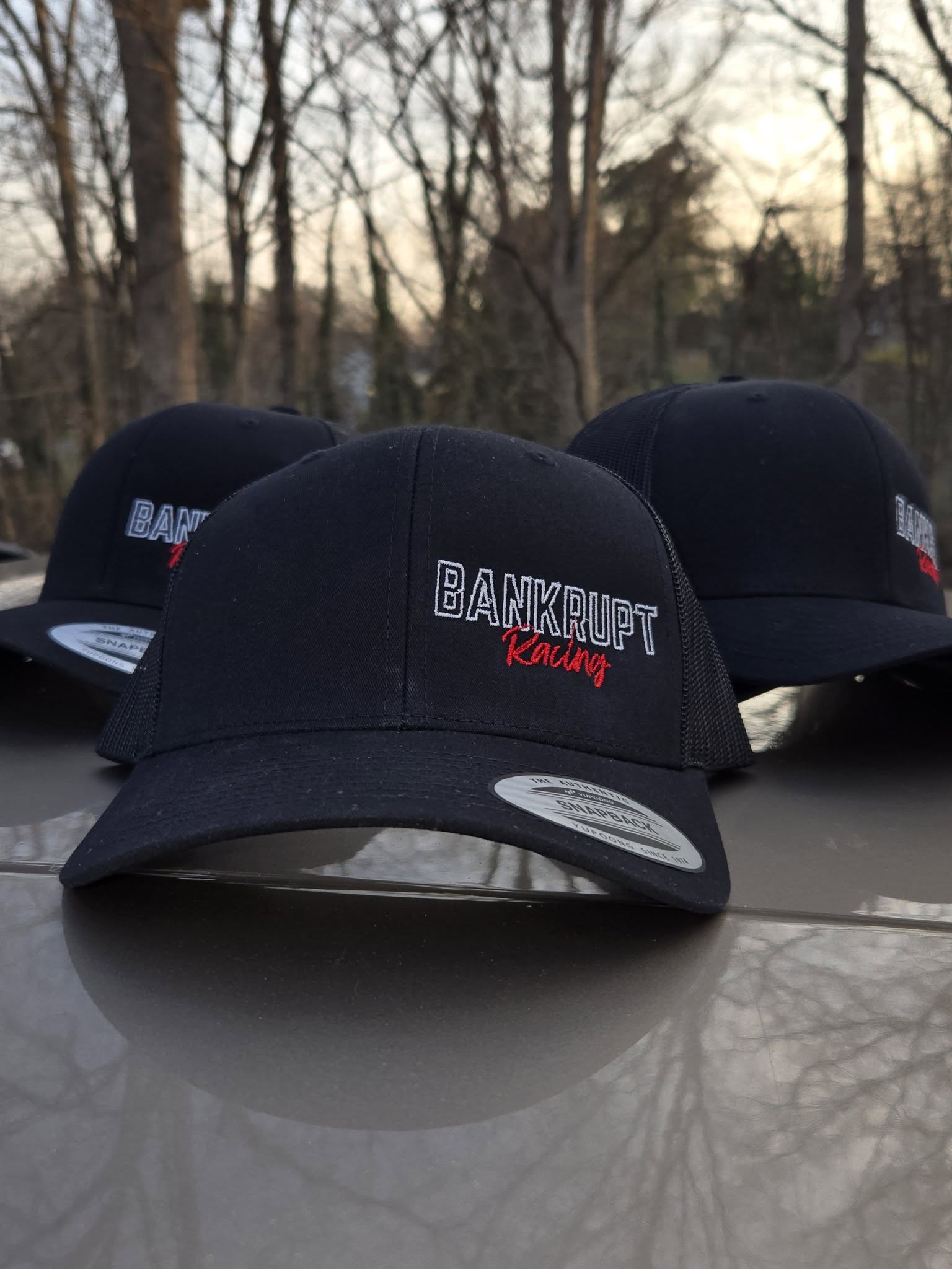 black embroidered hats with white and red motorsports team logo