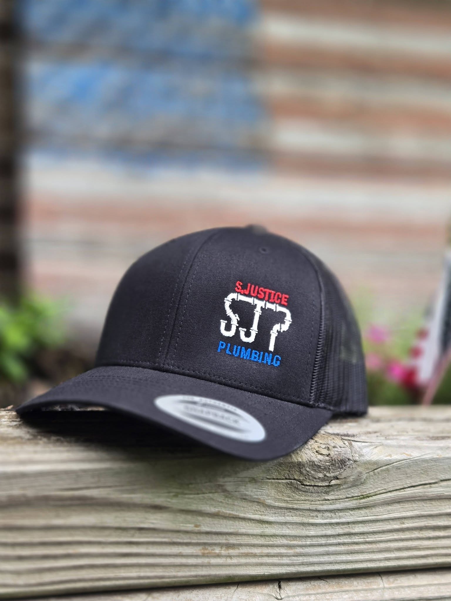black embroidered hat with red, white and blue plumbing logo
